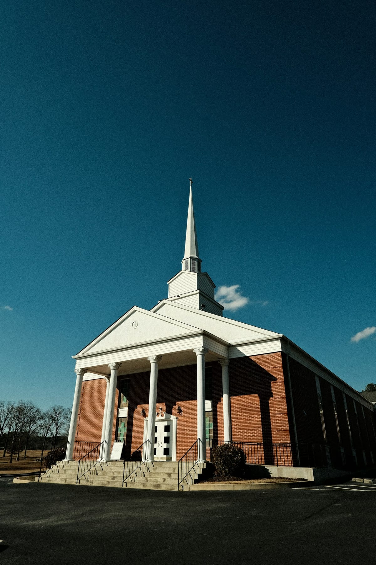 A brick church with white columns and a tall white steeple