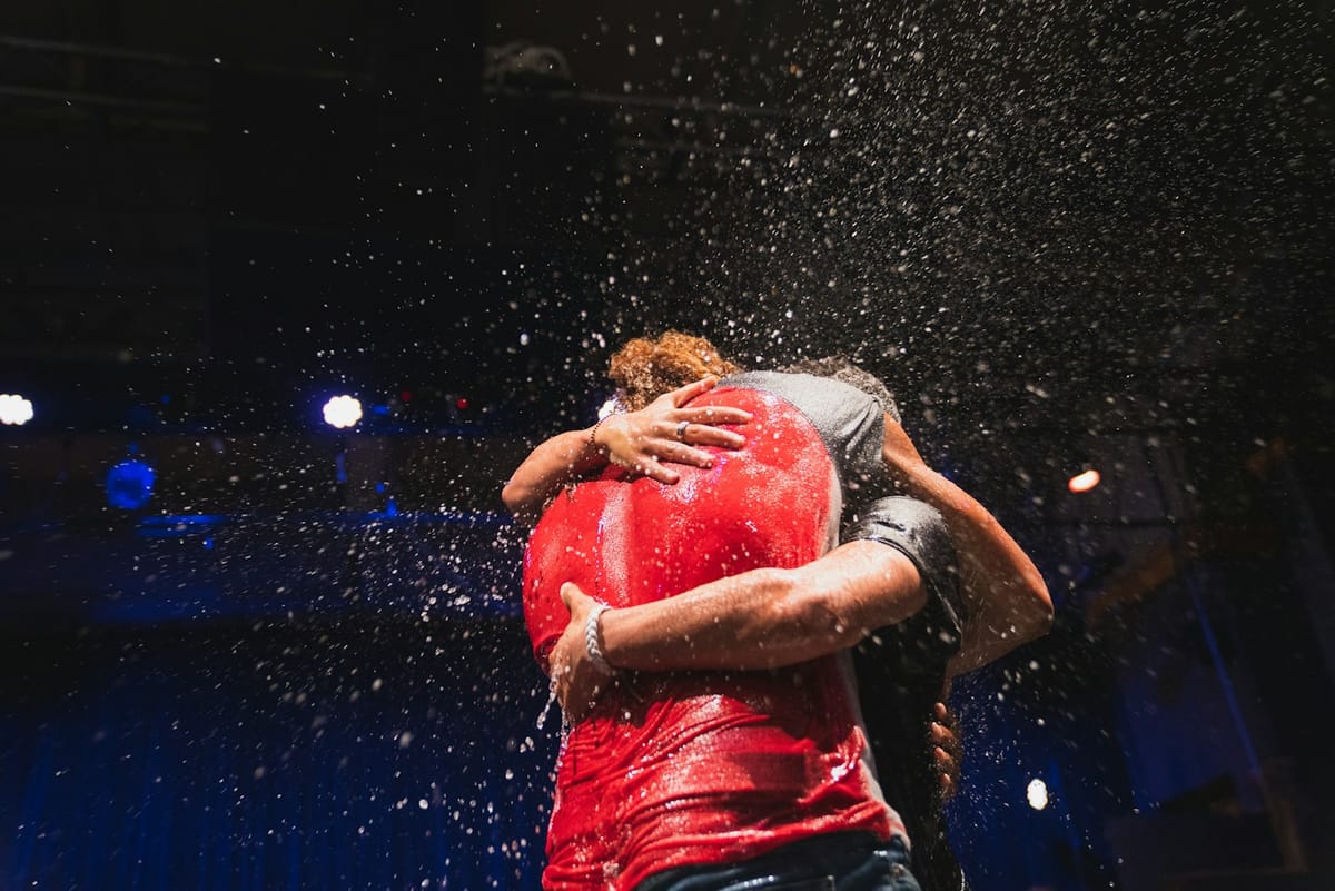 Two people embracing as water sprays around them