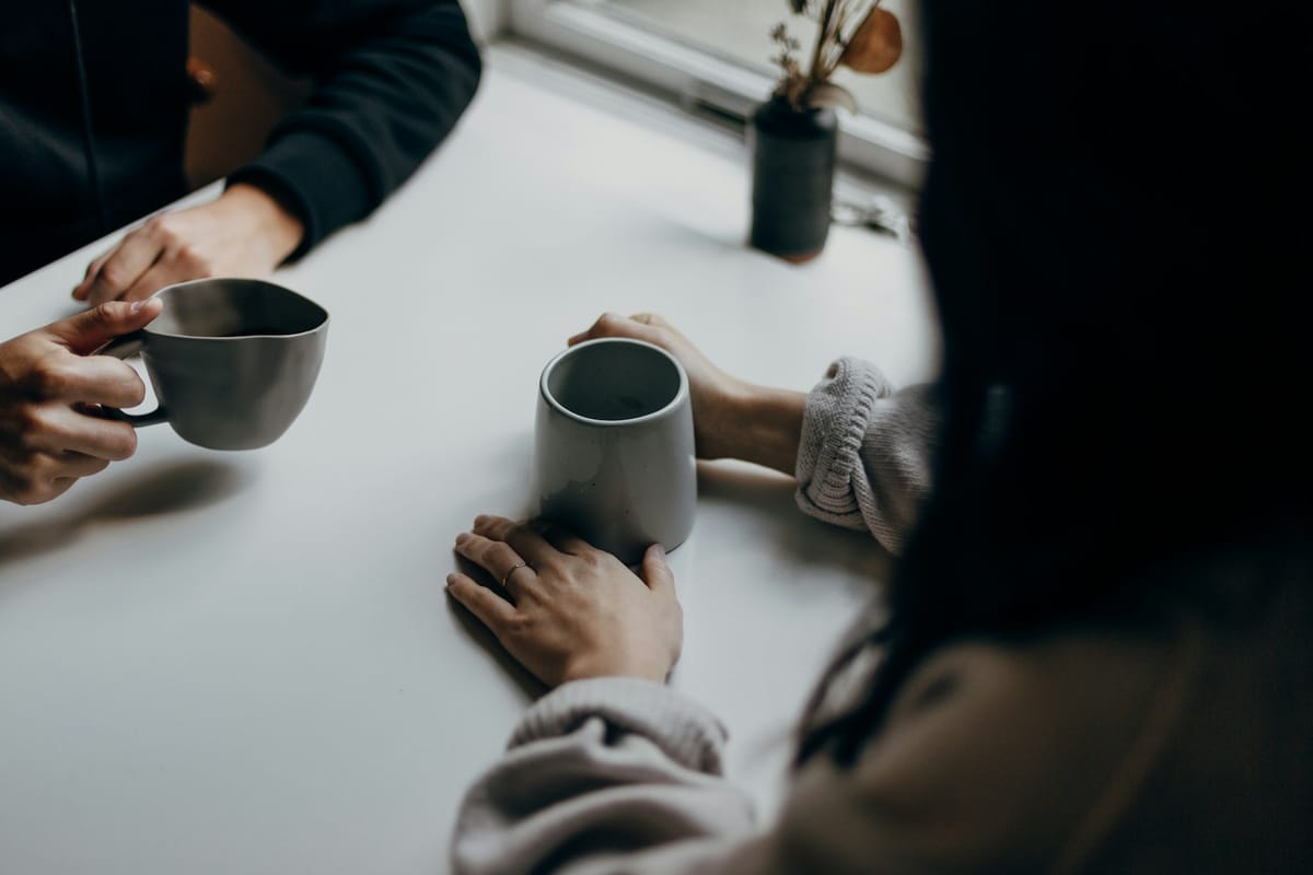 Hands around mugs at a table during a quiet conversation